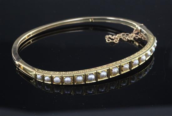 An Edwardian gold and graduated split pearl set hinged bangle,
